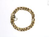 gros plan d'un bracelet en chaîne en or sur une surface blanche