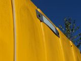 a close up of a yellow wall with a blue sky in the background