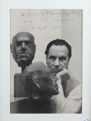 photographie en noir et blanc d'un homme assis à côté du buste d'un homme