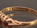 a close up of a gold ring with a red stone