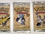 three packs of pokemon trading cards on a white surface