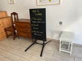 a chalk board in the corner of a room with a table and chair