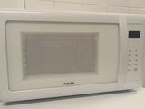 un micro-ondes blanc posé sur une machine à laver