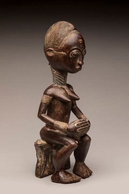 une statue en bois représentant une femme assise sur une souche d'arbre