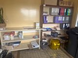 a room with a desk, shelves, and a refrigerator