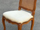 une vieille chaise avec un dossier et une assise en rotin, posée sur le trottoir