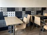 tables and chairs in a restaurant with a tiled wall behind them