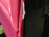 the door of a red truck with a rusted handle on it ' s side