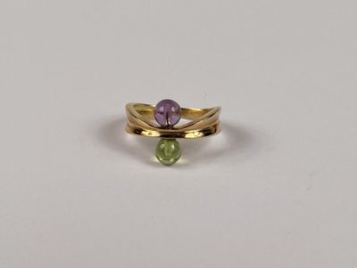 un gros plan d'une bague sertie d'une pierre verte et violette