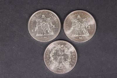 trois pièces d'argent posées sur une surface noire