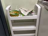 a small white shelf with food in it in a kitchen