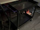 a black table with a metal shelf on it in the middle of a room