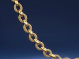 a gold necklace with a twisted link on a blue background