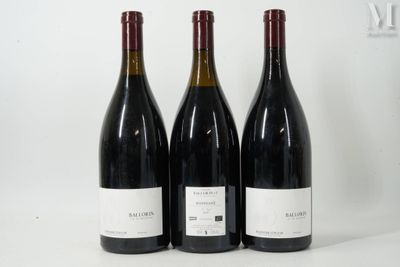 trois bouteilles de vin rouge sont alignées sur une surface blanche