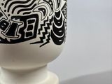 a white vase with a black and white design on it