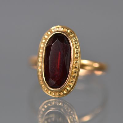 Gros plan sur une bague en or ornée d'une pierre rouge