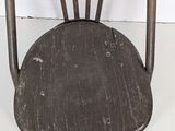 a wooden chair that has a black seat on it