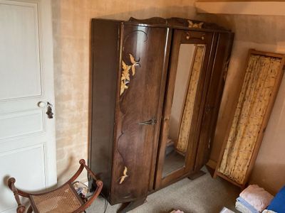 a wooden armoire with a mirror and a chair in the corner