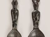 two silver spoons and a spoon with a statue on them