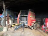 a tractor and a trailer in a barn with other farm equipment