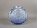 un vase en verre bleu posé sur une surface blanche