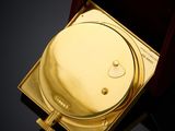 a gold toilet in a wooden box on a black surface