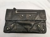 the black leather clutch bag has two zippers on the front of it