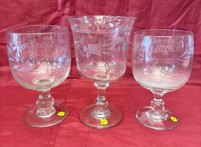 trois verres à vin vides posés sur une nappe rouge, sur fond rouge