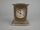a small silver clock with roman numerals on it