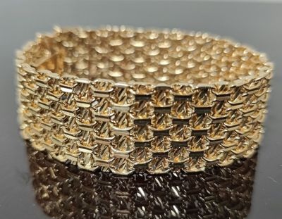 gros plan d'un bracelet en or sur une surface noire