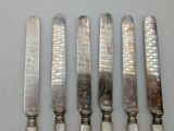 four silverware knives are lined up on a table