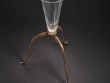 un vase ancien en verre posé sur un socle à base métallique