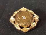 a gold brooch with a diamond in it on a black surface