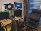 a desk with two computers and a chair in front of a window
