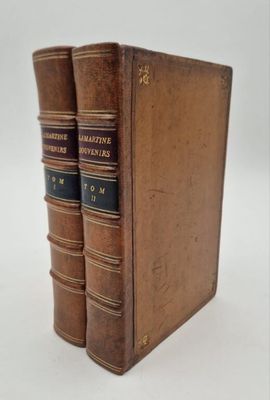 two old books sitting on top of each other on a white surface