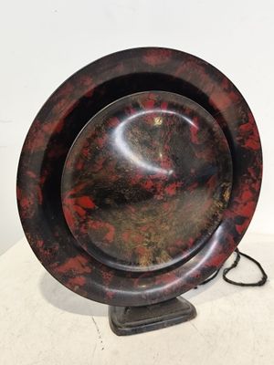 une assiette rouge et noire posée sur un support, sur une table