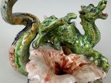 a ceramic sculpture of a dragon and a flower on a table