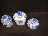 three blue and white vases sitting on top of a black surface