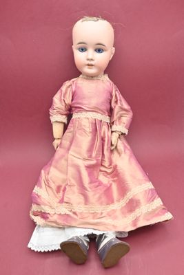 an old fashioned doll is sitting on a pink surface