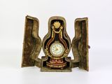a small clock inside of a wooden box on a white surface