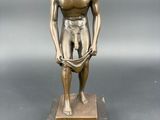 statue en bronze représentant un homme les mains dans les poches, posée sur un socle en marbre