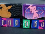 trois boîtes de cartes à jouer Pokémon posées sur une table