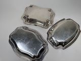 three silverplated trays on a white table with a white background