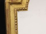 a mirror with a gold frame on a black wall