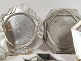 two silver dishes on a table next to each other