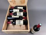 bottles of wine in a wooden box next to a bottle of wine