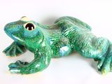 une figurine de grenouille verte posée sur une surface blanche