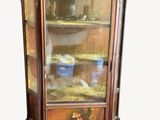a cabinet with a glass door that has a painting on it