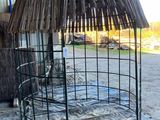 a metal cage with a thatched roof in the middle of a barn