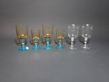 several different colored glass goblets are lined up on a gray surface